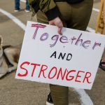 Protest sign reading "Together and Stronger."