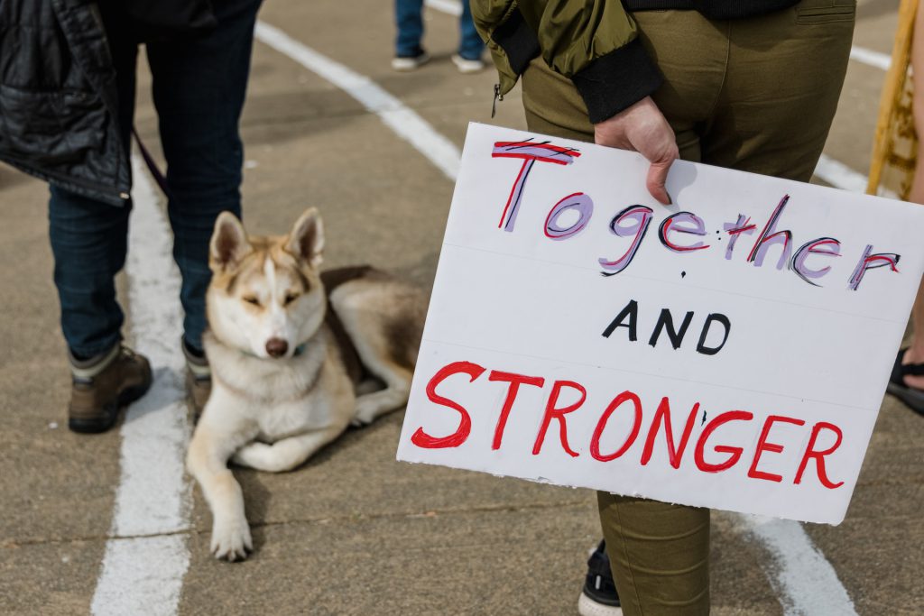 Protest sign reading "Together and Stronger."