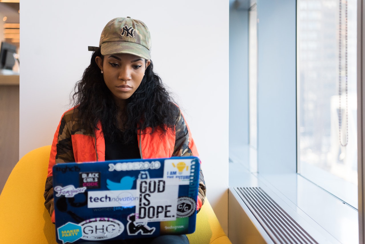 Black student and woman in tech working on her laptop.