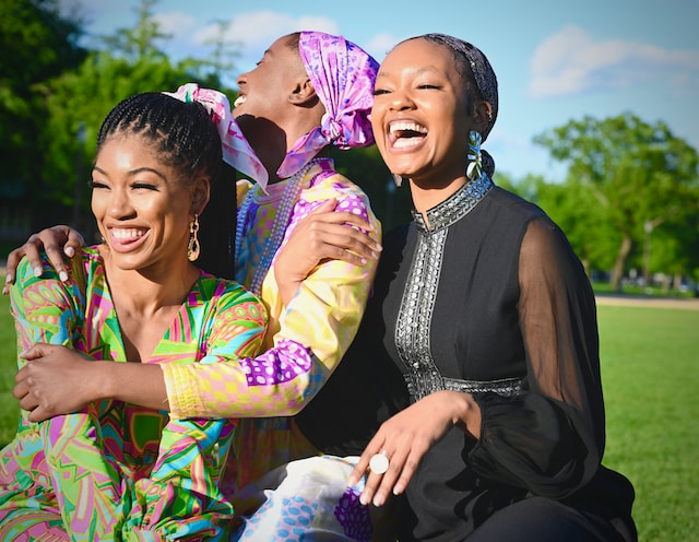Three black women laughing and embracing.